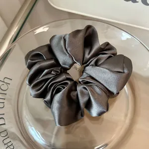 Macro detail of charcoal grey satin scrunchie with silky folds and metallic luster