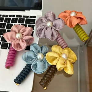 Detail shot of five colorful fabric flower hair clips with pearls on a laptop keyboard