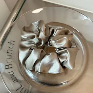 Detailed macro view of high-quality champagne satin scrunchie with silk texture on glass tray