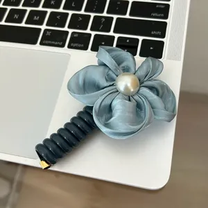 Detail of silk flower hair tie with pearl center on a laptop keyboard background