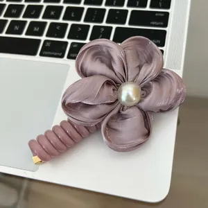 Detail of mauve satin flower hair clip with pearl center on laptop keyboard background