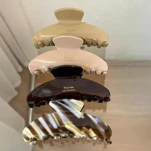 Vertical stack of four acetate shark hair claws in brown, cream, pink, and tortoiseshell