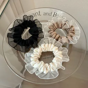 Tres coleteros de encaje de organza en negro, caqui y crema en una bandeja decorativa