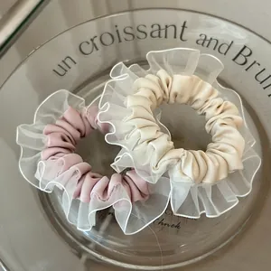 Detalle de coleteros de organza rosa y beige con base de satén en bandeja