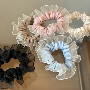 Detalle de gomas de pelo de satén con borde de encaje de organza en colores pastel suaves