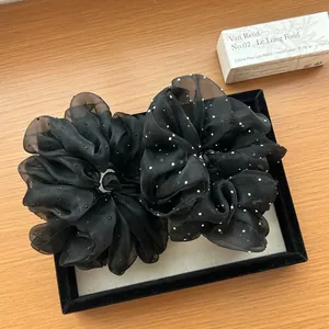 Detail of black organza scrunchie with white polka dots on a velvet display tray