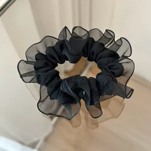 Detalle de coletero de organza negra y satén con textura en capas y volantes suaves