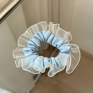 Detalle de coletero de satén azul claro con borde de encaje de organza blanco en capas