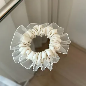Detalle de coletero de organza crema con volantes en capas sobre superficie de espejo