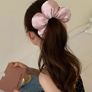 Chouchou fleur 3D en satin rose avec finition brillante porté par le modèle