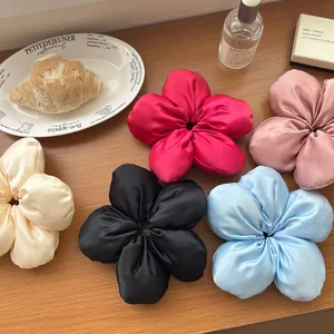 Détails de grands chouchous à fleurs en satin en cinq couleurs élégantes sur une table