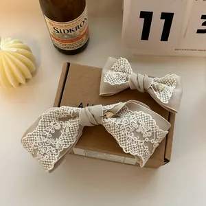 Detail of two French lace bow hair clips in various sizes on a rustic paper box