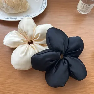 Vue détaillée des chouchous fleurs en satin noir et crème posés sur une table en bois