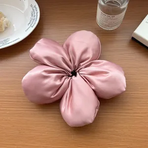Gros plan sur un chouchou fleur en satin rose brillant posé sur une table en bois