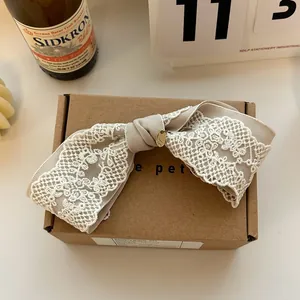 Detail of vintage beige lace bow hair clip with gold metal tag on cardboard packaging