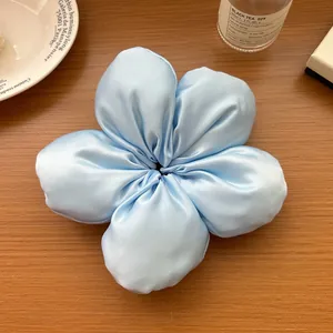Détail d'un chouchou fleur en satin bleu clair avec éclat perlé sur table en bois