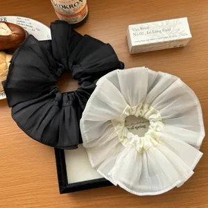 French oversized pleated hair scrunchies in black and cream white on a wooden desk