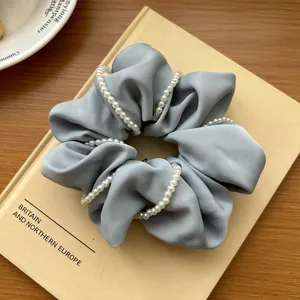 Detailed close-up of grey satin scrunchie with elegant faux pearl chain on a book