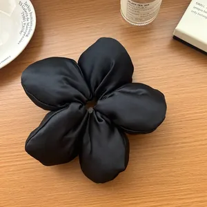 Gros plan d'un chouchou fleur 3D en satin noir haut de gamme sur une table en bois