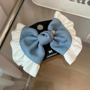 Detail of French vintage bow hair clip with blue twill fabric and white lace trim