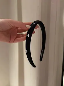 Détail d'un serre-tête noir rembourré avec des nœuds argentés et marquage artisanal