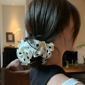 Elastico scrunchie in seta bianca a pois neri acconciato in uno chignon basso