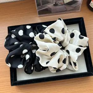 Dettaglio di elastici scrunchie a pois bianchi e neri in raso per acconciature francesi
