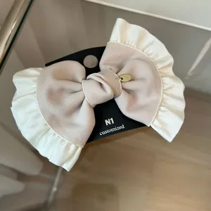 Detail of French vintage bow hair clip with beige twill fabric and white ruffle edges