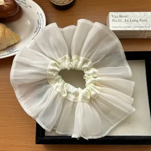 Detailed view of a white oversized organza scrunchie with elegant ruffled layers