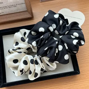 Scrunchies a pois bianchi e neri esposti su un raffinato vassoio di velluto