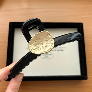 Close-up of black hair claw clip with golden metal plate featuring numbers 1-10