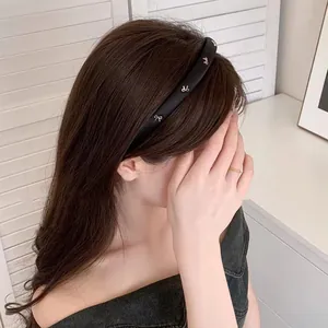 Serre-tête noir élégant en éponge avec nœuds métalliques porté par un modèle de profil