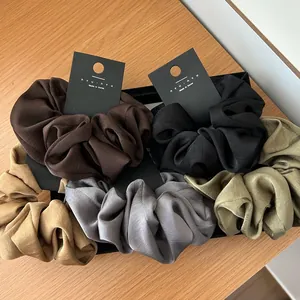 Close-up of silk texture hair scrunchies in earth tones displayed in a black gift box