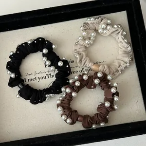 Detail of high-elastic scrunchies with white pearls and silver studs in three colors