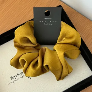Detail of vintage olive green satin scrunchie with silky ripple texture on display card