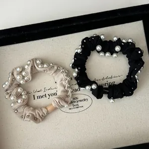 Close-up of elegant beige and black pearl hair scrunchies with satin texture details