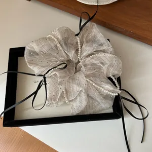 Detailed texture of pleated champagne organza hair scrunchie with pearls and rhinestones