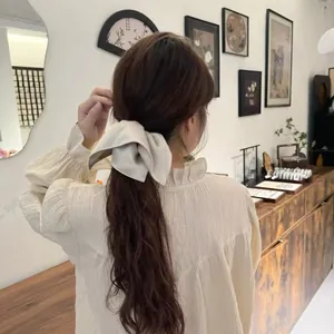 Elegant cream satin bow hair scrunchie shown on model back view for hairstyle styling