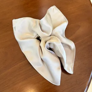 Detail view of champagne silk satin scrunchie with soft pleats and glossy texture