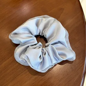Detail of silk satin scrunchie with mesh lace trim in blue on a wooden surface