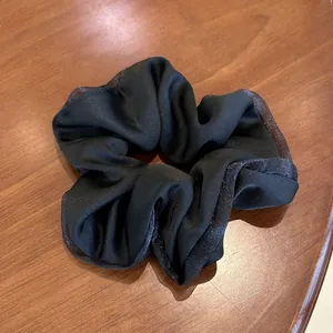 Close-up of black satin hair scrunchie with glitter lace edge on wood background