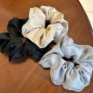 Three elegant satin scrunchies with glitter mesh lace edge on dark wood background