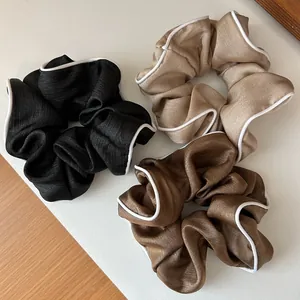 Trois chouchous élégants en satin noir, beige et marron avec bordure ondulée blanche