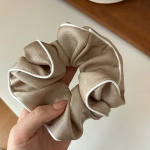 Gros plan d'un chouchou en satin champagne avec un élégant liseré blanc contrasté