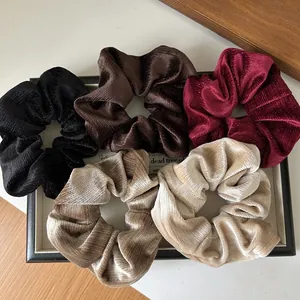 Détail de cinq chouchous en velours plissé aux couleurs classiques sur un plateau