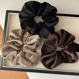 Détail de chouchous en velours pailleté noir, doré et marron sur un plateau d'exposition