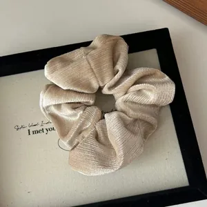 Détail de la texture d'un chouchou en velours doré champagne avec motif côtelé