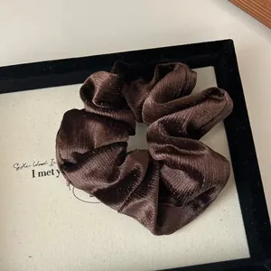 Détail d'un chouchou en velours marron avec texture scintillante et plis en tissu