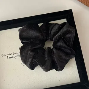 Détail d'un chouchou en velours noir avec paillettes argentées dans un cadre chic