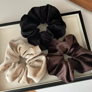 Lot de trois chouchous en velours pailleté en couleurs noir, marron et beige clair
